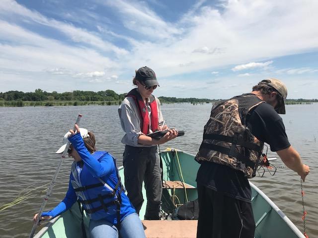 学生们在湿地的船上工作. Amy Corrazzino-Lyon拍摄.